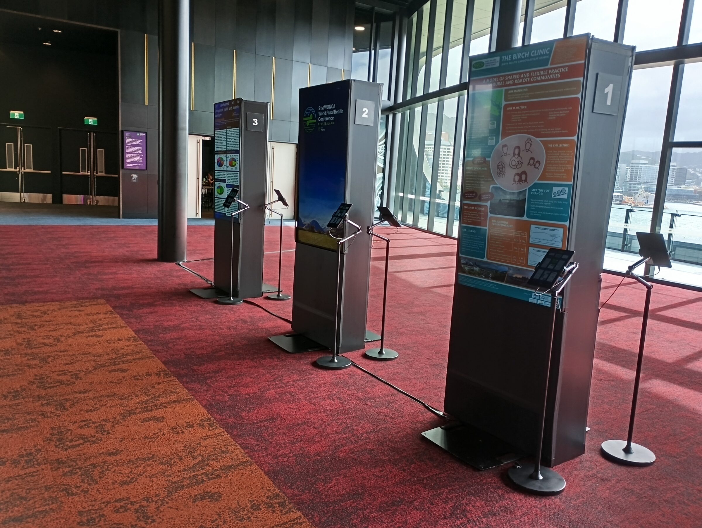 Digital poster displays installed in a conference venue foyer.